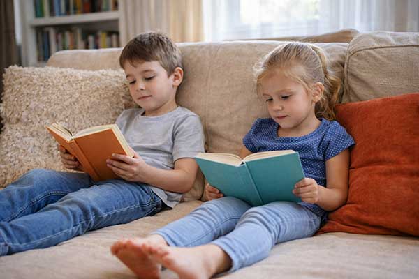 Zwei Kinder lesen entspannt auf dem Sofa – ruhige und bildschirmfreie Beschäftigung für mehr Konzentration