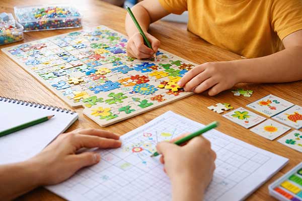 Kind beschäftigt sich mit Puzzle und Arbeitsblatt – Konzentration bei Kindern spielerisch fördern ohne Bildschirm